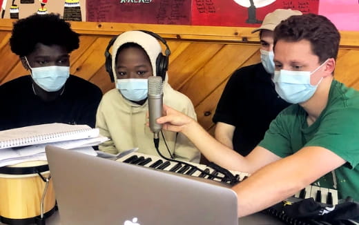 a group of people wearing masks and using a laptop