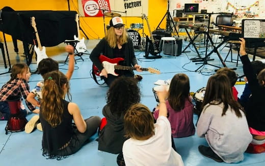 a person playing guitar in front of a group of people