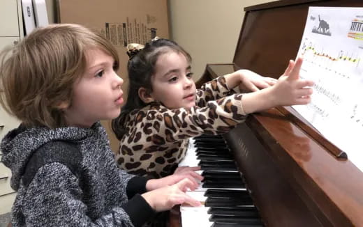 a couple of girls playing piano