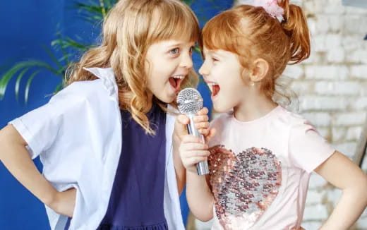 a couple of girls singing into a microphone