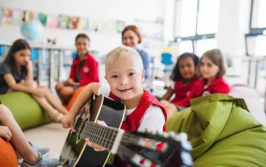 a boy playing a guitar in a classroom