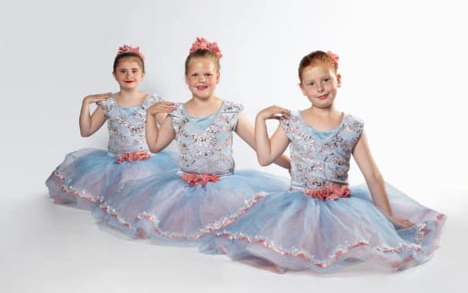 a group of girls in dresses sitting on a blue ball