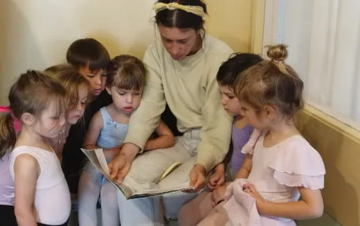 a person reading a book to a group of children