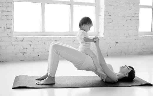 a person sitting on a mat with a baby on the lap