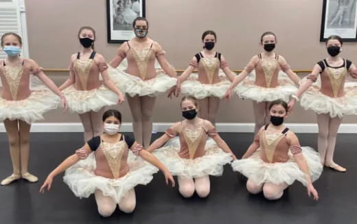 a group of women wearing white dresses and dancing