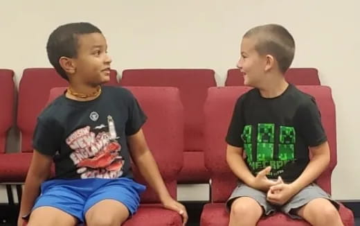 two boys sitting on a red couch