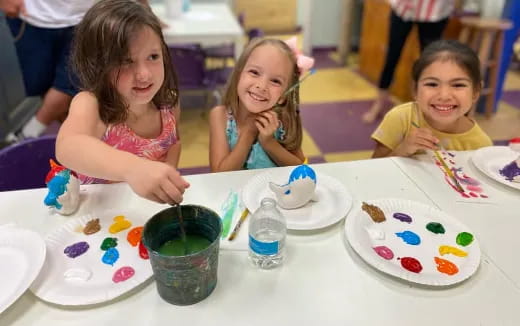 a group of children sitting at a table with food
