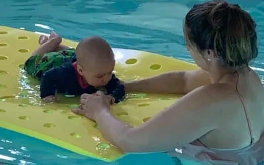 a person and a baby in a pool