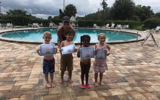 a group of children posing for a photo by a pool