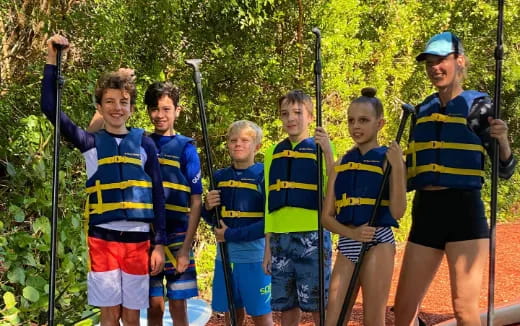 a group of boys in life vests holding bows and arrows