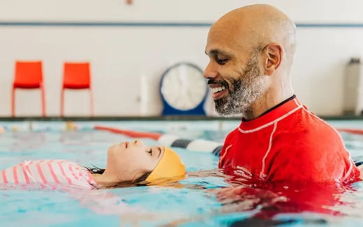 a man in a pool with a baby in it