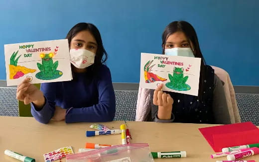 a couple of girls holding up drawings