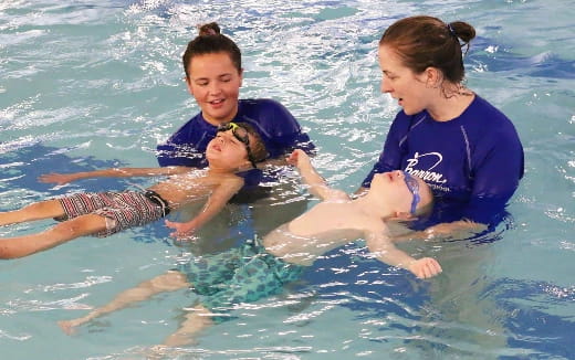 a couple of kids in the water with a dolphin