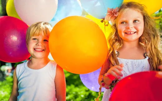 a couple of children holding balloons