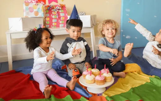 a group of kids sitting on a bed with a birthday cake