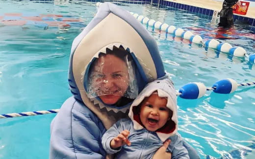 a person and a baby in a pool with a floaty