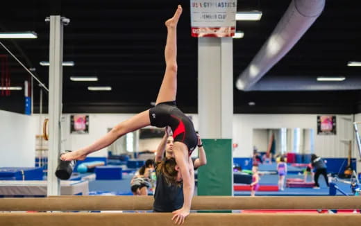 a person doing a handstand on a mat in a gym