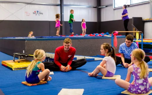 a group of people sitting on a mat in a gym