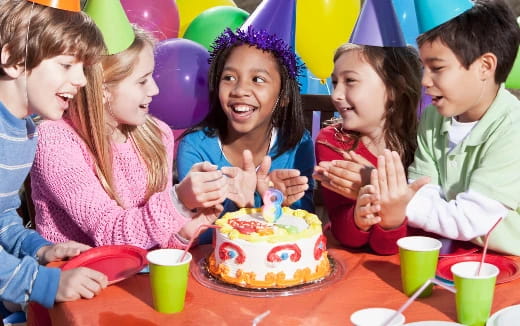 a group of children around a birthday cake