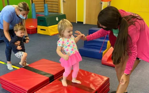 a person and children playing on a mat