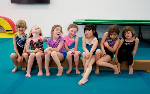 a group of children sitting on a blue mat