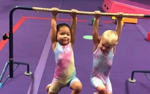 a couple of young boys in a gym with bars