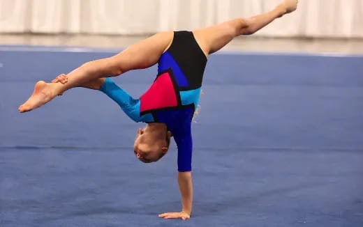 a woman doing a handstand on a blue surface