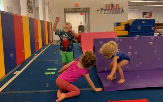a group of kids playing on a mat in a gym