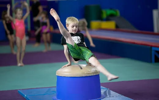 a boy jumping on a blue mat