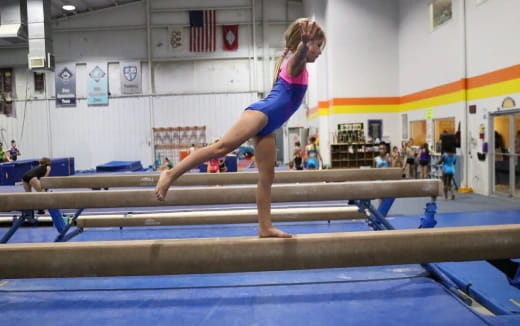 a woman jumping over a bar