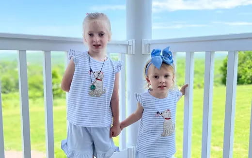two children standing next to a white fence