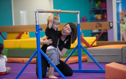 a person holding a child on a bar