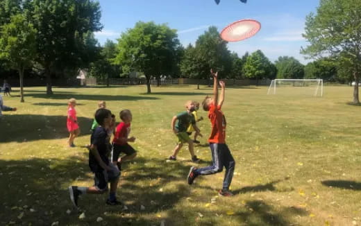 a group of kids playing frisbee in a park