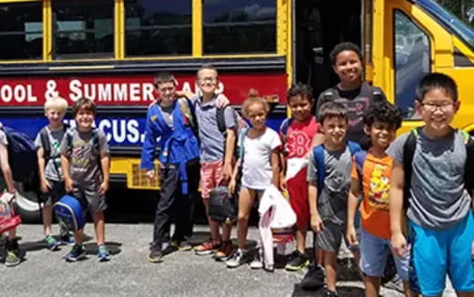 a group of children standing in front of a bus