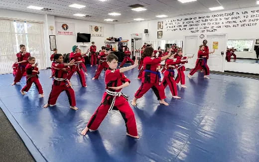 a group of children in red uniforms dancing in a room