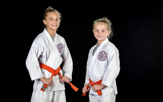 a couple of girls in karate uniforms