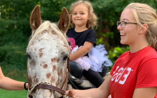 a woman and a child riding a horse