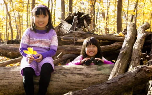 two girls sitting on a log