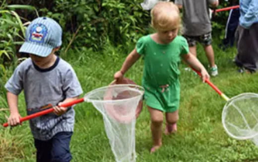 a couple of children playing with a bucket of water