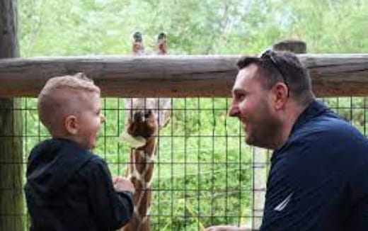 a person and a boy looking at a monkey in a cage