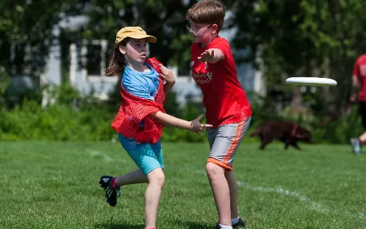 a couple of people play frisbee in a park