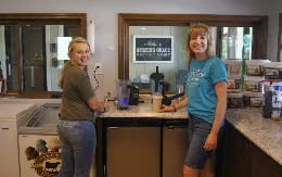 a couple of women standing in a kitchen