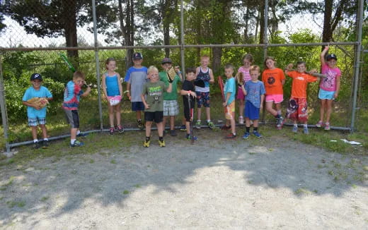 a group of kids standing in front of a fence