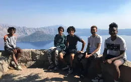 a group of men sitting on a ledge overlooking a lake