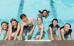 a group of people in swimsuits in front of a pool