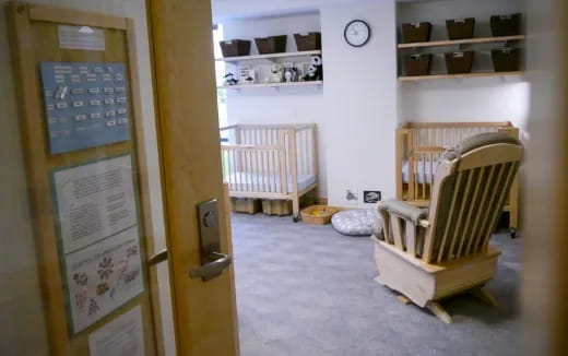 a room with a baby crib and a chair