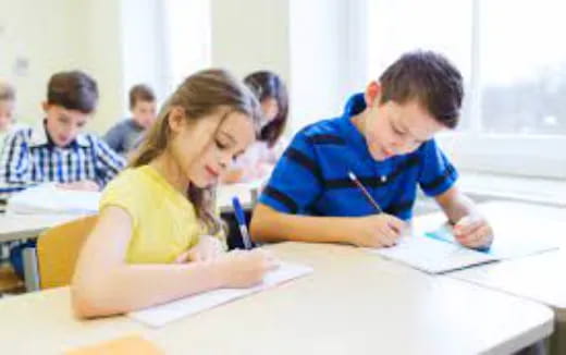 a group of children sitting at desks writing on paper