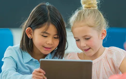 a couple of children looking at a laptop