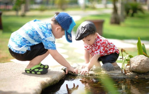a couple of children playing in a pond