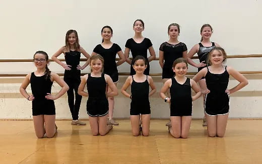 a group of women in black leotards posing for a photo